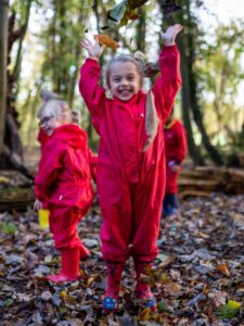 Nursery Forest School girl jumping leaves